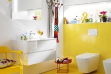 23 a colorful bathroom with a yellow tile wall and floor plus a chair and all white around looks quirky and cool