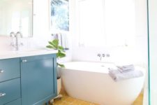 26 an airy and cheerful bathroom with a yellow tile floor and a teal vanity plus all whites to create a bold look