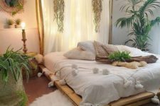 a boho tropical bedroom with a pallet bed, a lit up headboard of fabric, woven touches and tropical plants