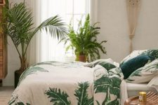 a boho tropical space with a macrame hanging, tropical bedding, wooden furniture and potted plants