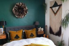 a bold boho bedroom with a hunter green accent wall, mustard touches, a macrame hanging and black details for drama