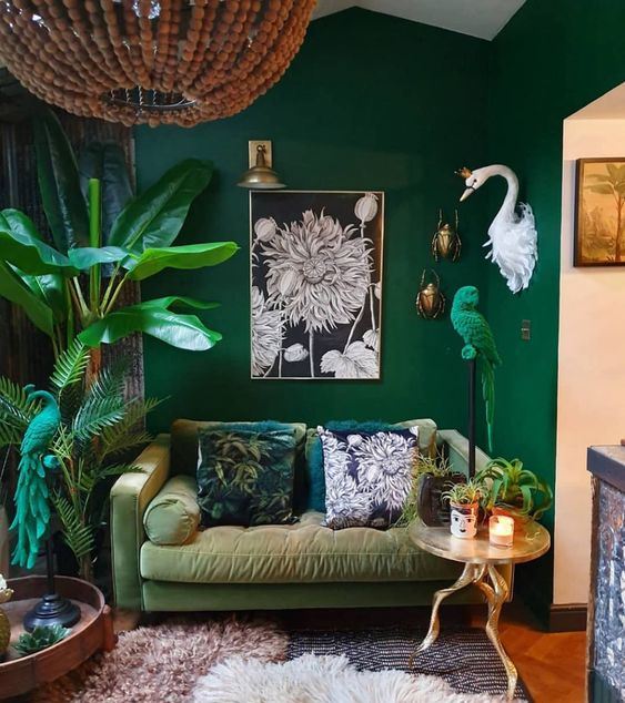 a bold living room with emerald walls, a muted grene sofa, potted plants and a parrot figurine in emerald