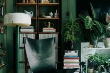 a bold living room with green walls, a hunter green leather chair, a green lamp and lots of plants feels comfy