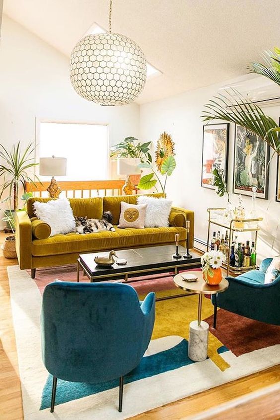 a bold mid-century modern living room with a mustard velvet sofa and a color block rug plus lots of tropical plants