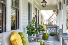 a bright and welcoming summer porch with citrus trees, a neutral loveseat with bright pillows and side tables