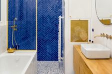 a bright bathroom with a bold blue accent tile, Dolmatin print tile, touches of gold and a wooden vanity