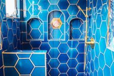 a bright blue bathroom clad with hexagon tiles and highlighted with gold touches for more chic