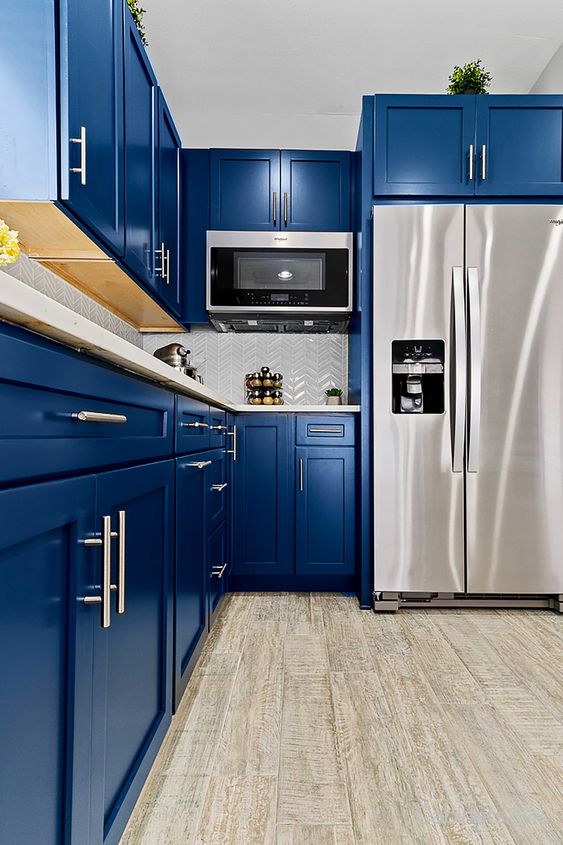a bright blue kitchen with a white chevron tile backsplash, stainless steel appliances and simple handles