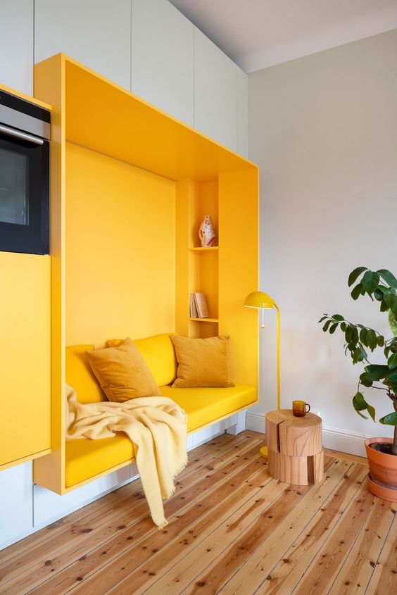 a bright contemporary living room with a bold yellow niche with a sofa and shelves and a matching floor lamp