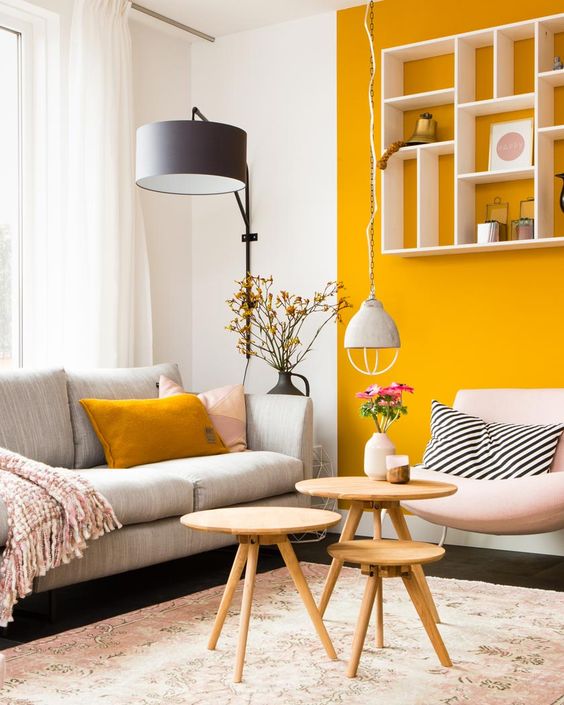 a bright contemporary living room with a mustard accent wall and a pillow plus simple neutrals and black touches