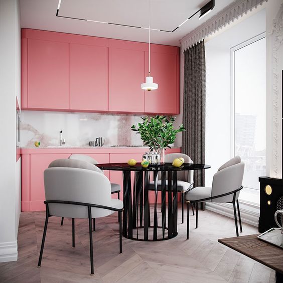 a bright pink modern kitchen with sleek cabinets, a shiny backsplash and a pendant lamp plus an elegant dining space
