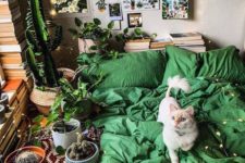 a catchy bedroom with neutral walls, stacks of books, a gallery wall and bright green bedding plus lots of cacti