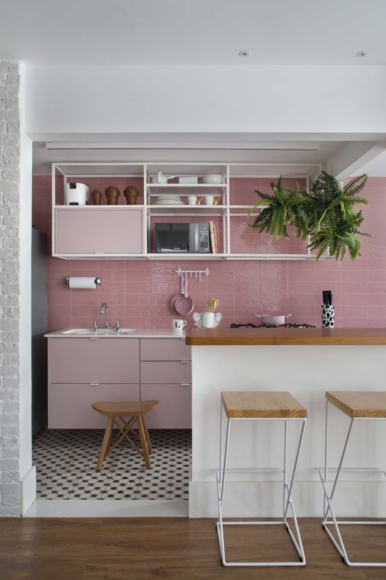a catchy kitchen with a pink tile backsplash and pale pink cabinets, open shelving and a large white kitchen island