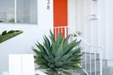 a catchy modern entrance with an orange door, a black spotlight, a white lounger and a couple of large agaves