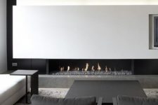 a chic contrasting living room with a white lit up wall with a fireplace, a white sofa, a black table and chairs is wow