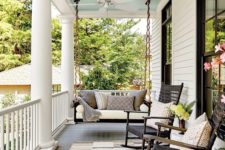a chic farmhouse porch with a hanging daybed, a couple of rockers and neutral textiles