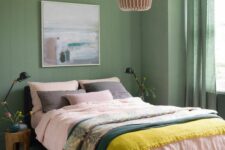 a chic green bedroom with a bed and bright bedding, a pendant lamp, some vases and decor and baskets with blankets