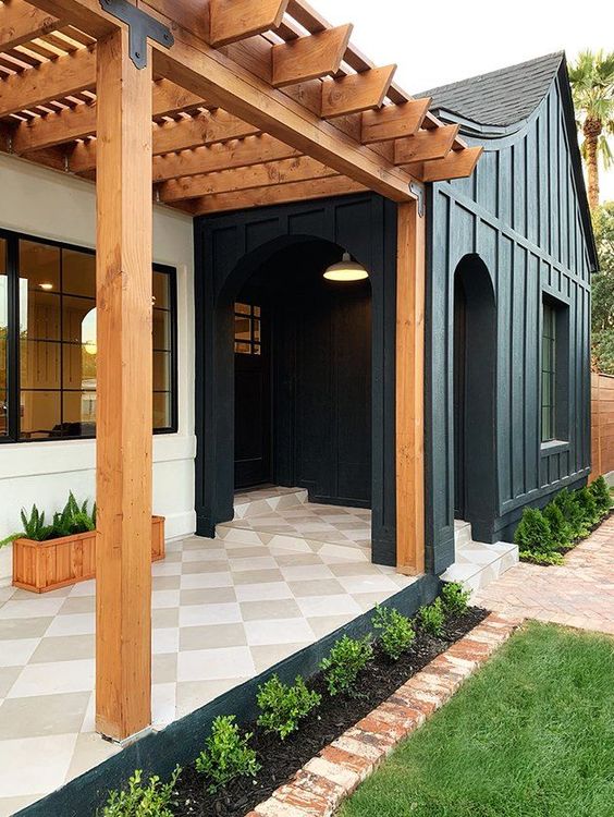 a chic modern front porch with a checked tile floor, potted greenery, a pendant lamp and navy paneling is elegant