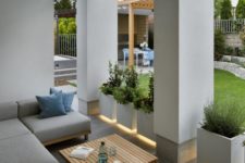 a chic modern porch in grey, with a sectional sofa, floating planters and built-in lights