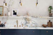 a chic navy kitchen with only lower cabinets, a marble countertop and backsplash, sconces and an open shelf