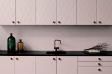 a chic pale pink kitchen with patterned and sleek cabinets, black countertops for a bold contrast