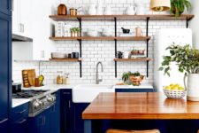 a classic blue kitchen with a white subway tile backsplash, white countertops and wooden open shelves