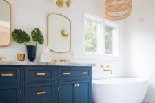 a coastal bathroom with white walls, navy and white mosaic tiles, navy vanities and touches of wicker