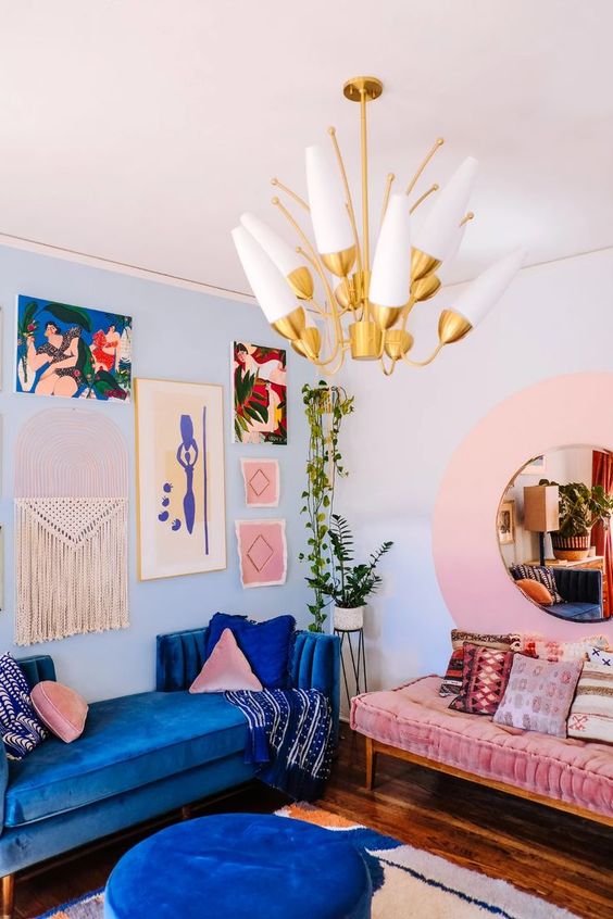 a colorful living room done in bold blue and pink, with a creative gallery wall, a bold blue sofa and a light pink daybed