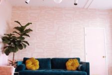 a colorful living room with printed pink walls, a striped pink ceiling, a pink chair and pillows plus touches of teal and mustard