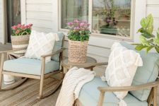 a farmhouse summer porch with wooden furniture, aqua upholstery, neutral pillows, blooms in woven plants is very welcoming