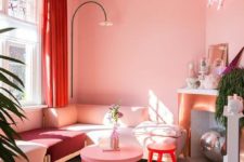 a glam living room with light pink walls and a ceiling, a pink sectional and a coffee table, a neon light and a red stool