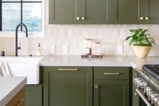 a grass green kitchen with gold and brass touches, black fixtures and a catchy geometric tile backsplash