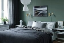 a green Scandinavian bedroom with a bed with monochromatic bedding, white nightstands, a pendant lamp and gold sconces