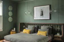 a green bedroom with a bed with an extended headboard and printed bedding, pendant lamps and some art