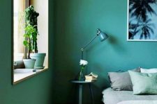 a green bedroom with some comfy furniture, green and grey bedding and potted cacti