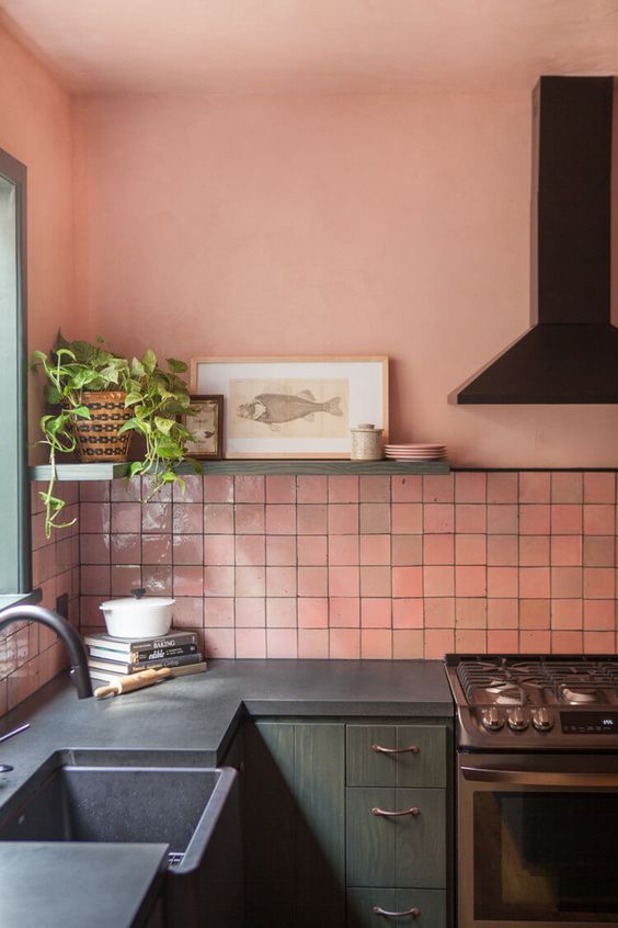 a kitchen with pink walls, a pink tile backsplash, dark green cabinets and black wooden countertops looks very catchy