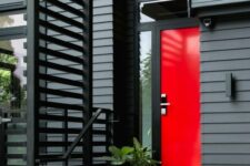a laconic and bold modern entrance with a black wooden beam cover, a hot red door with glass panes and potted greenery is amazing