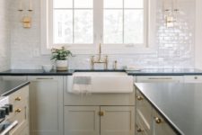 a light grey kitchen with black countertops, white tiles and gold and brass touches for a shiny touch