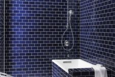a minimalist bathroom clad with navy subway tiles and accented with white grout and items is extra bold
