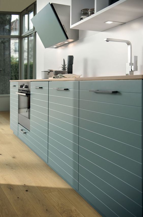 a minimalist hunter green kitchen with striped cabinets, butcherblock countertops and a matte glass backsplash