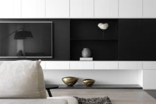 a minimalist living room with a black and white wall, a built-in TV, neutral furniture and chic decor