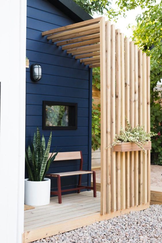 a modern and simple private porch with a slab screen, a wooden chair and some potted plants is veyr welcoming