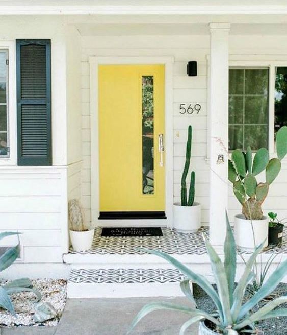 a modern desert porch with potted cacti, mosaic tiles on the porch and a bright sunny yellow door