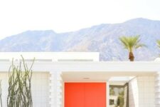a modern entrance with fiery red doors, cacti and agaves, some greenery around the entrance is a cool space with a desert feel