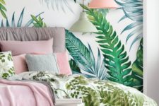 a modern tropical bedroom with a tropical leaf wall, an upholstered bed, some side tables and cool pink and green bedding