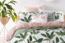 a modern tropical bedroom with a white brick wall, printed bedding with leaves and flamingos and potted plants