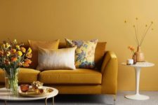 a monochromatic living room with yellow walls, a rust-colored sofa, a yellow rug and rust and yellow touches