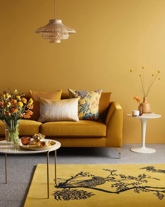 a monochromatic living room with yellow walls, a rust-colored sofa, a yellow rug and rust and yellow touches