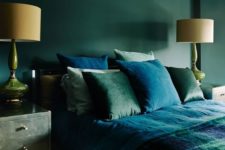 a moody refined bedroom with hunter green walls, green nightstands, green and blue bedding and refined lamps