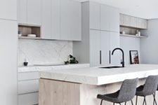 a neutral minimalist kitchen with dove grey cabinets, a white marble backsplash and countertops, a wooden kitchen island and felt stools
